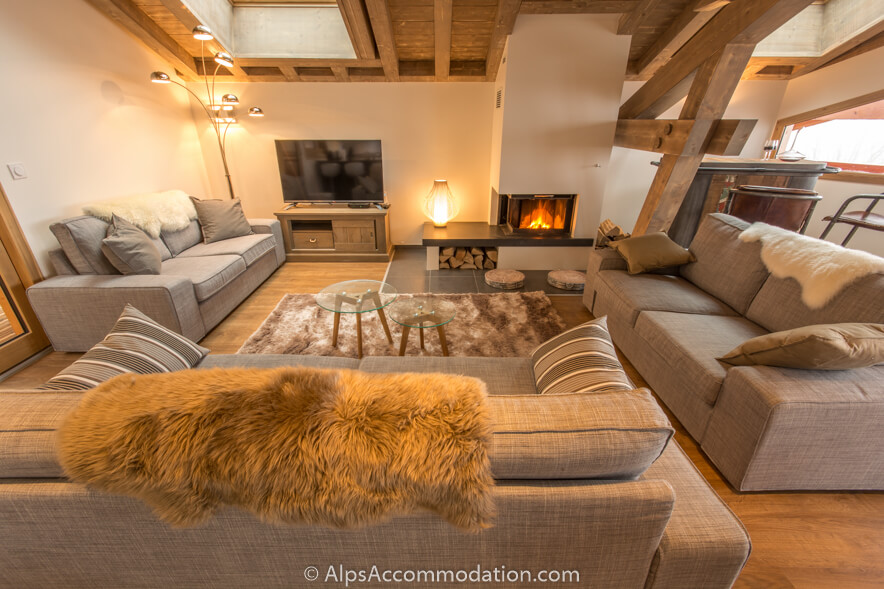 Chalet 75 Samoëns - Spacious living area with comfortable seating in front of a log fire and large LCD TV